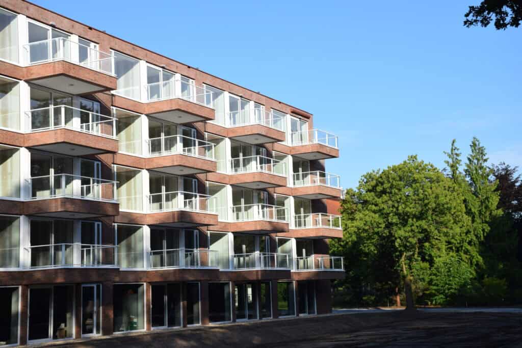 Modern woongebouw met ruime appartementen en balkons, omgeven door groen en natuur.