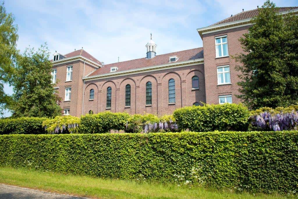 Laverhof verzorgingshuis in kleurrijke tuin met groen en bloemen, rustgevende omgeving voor ouderen.
